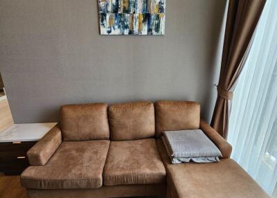 Brown sectional sofa in a living room with a painting hanging on a gray wall