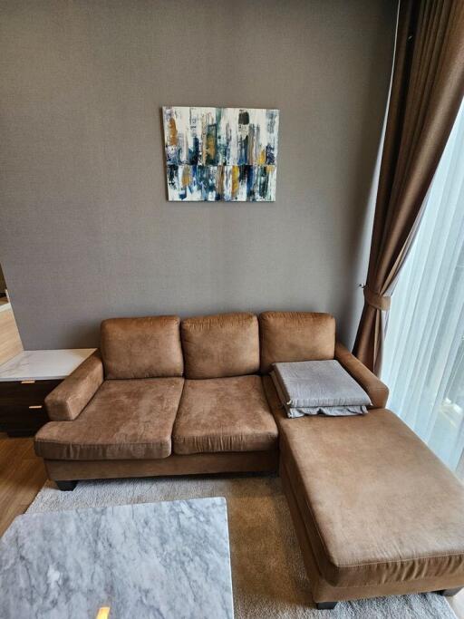 Brown sectional sofa in a living room with a painting hanging on a gray wall
