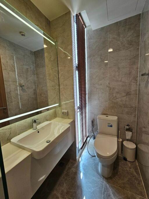 Modern bathroom with large mirror, sink, and toilet