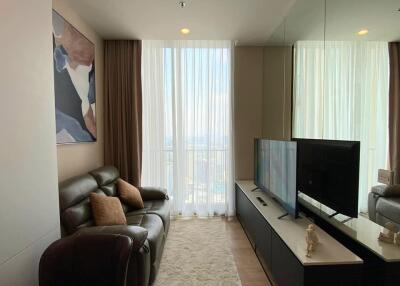 Modern living room with large window, leather sofa, wall art, TV, and mirrored wall