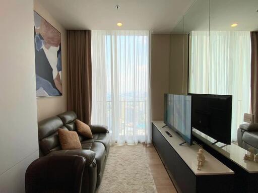 Modern living room with large window, leather sofa, wall art, TV, and mirrored wall