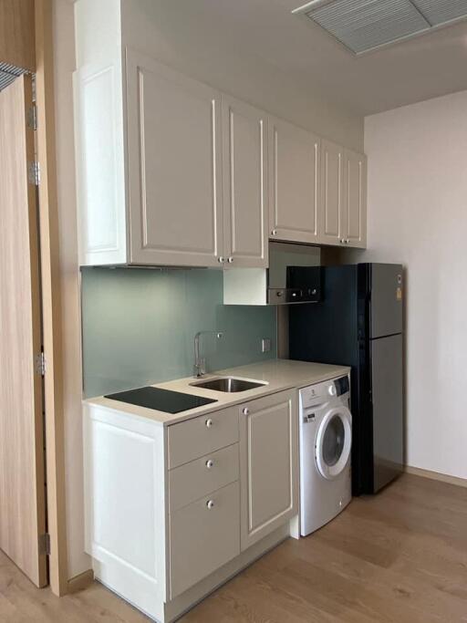 Compact kitchen with white cabinets, black refrigerator, washing machine, and induction cooktop