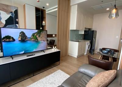 Modern living area with a flat-screen TV, kitchen, and dining table