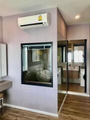 Modern bedroom with wall-mounted air conditioner and view into adjacent laundry room