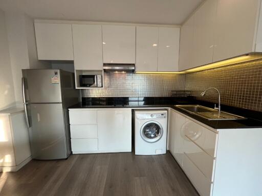 Modern kitchen with white cabinets, stainless steel appliances, and wooden flooring