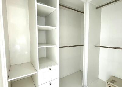 Spacious walk-in closet with white shelving and drawers