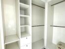 Spacious walk-in closet with white shelving and drawers