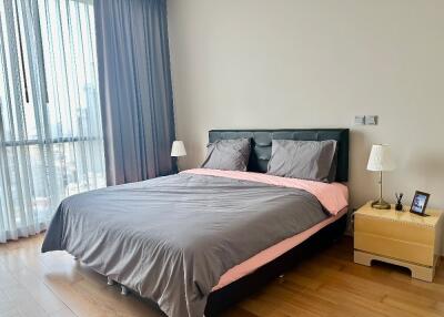 Modern bedroom with large bed, wooden floor, and bedside tables