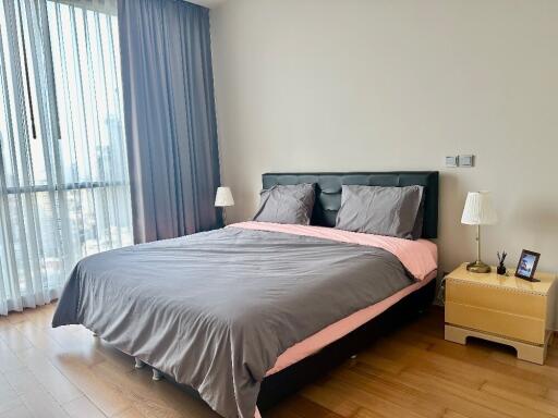Modern bedroom with large bed, wooden floor, and bedside tables