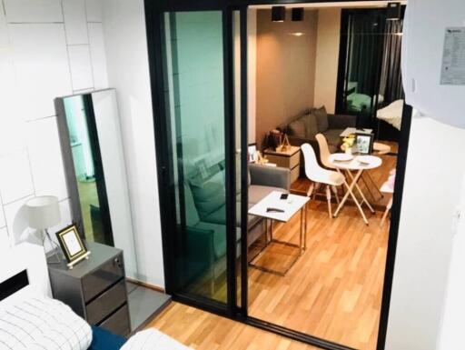 Bedroom with sliding glass doors leading to a living area with a sofa, dining table, and chairs.