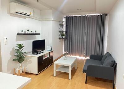 Modern living room with a sofa, coffee table, TV, potted plants, and wall-mounted air conditioner