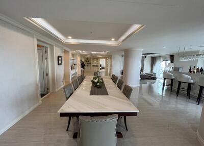 Elegant dining area with a long marble table, chairs, and open view of the living space.