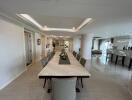 Elegant dining area with a long marble table, chairs, and open view of the living space.