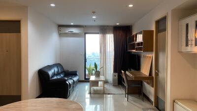 Living room with black leather sofa, wall-mounted TV, and work desk