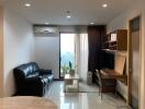 Living room with black leather sofa, wall-mounted TV, and work desk