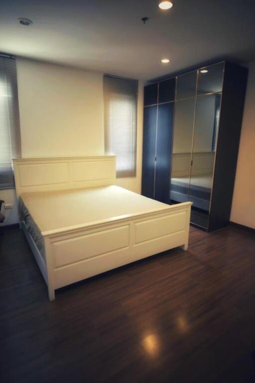 Spacious bedroom with wooden floors, large bed, and mirrored wardrobe