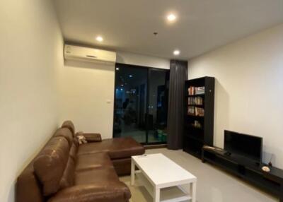 Modern living room with leather sofa, coffee table, TV cabinet, and bookshelf