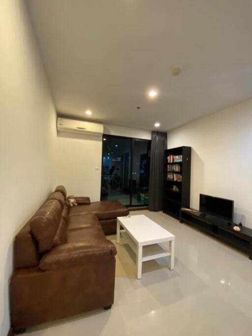 Modern living room with leather sofa, coffee table, TV cabinet, and bookshelf
