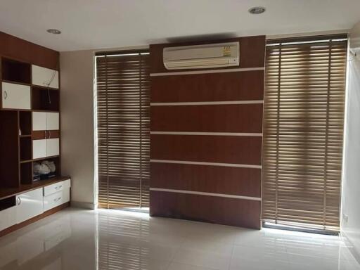 Living room with window blinds, wall air conditioner, and built-in shelves