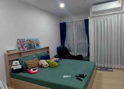 A modern bedroom with green bedding and various items on the bed