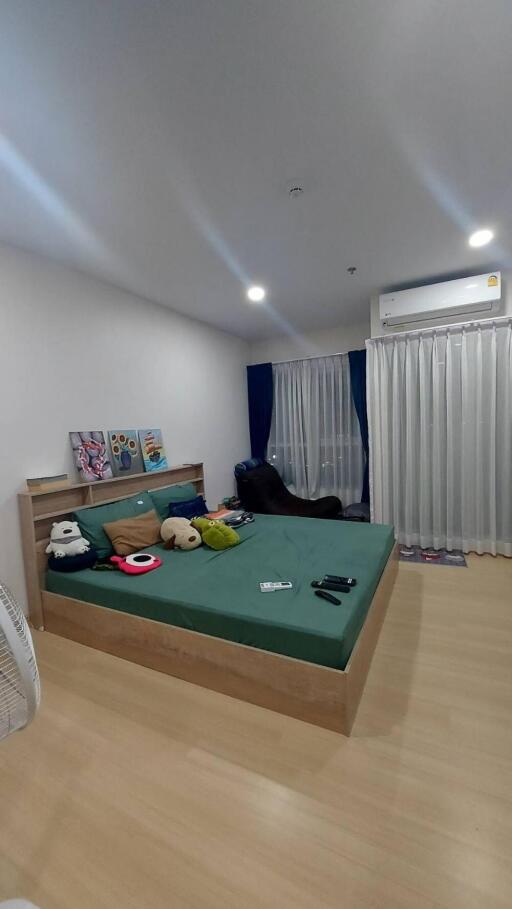 A modern bedroom with green bedding and various items on the bed