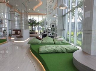 Modern lounge area with large windows and green cushioned seating