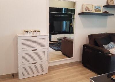 Modern living room with a sofa, wall-mounted shelves, a mirror, and a cabinet.