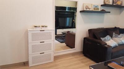 Modern living room with a sofa, wall-mounted shelves, a mirror, and a cabinet.