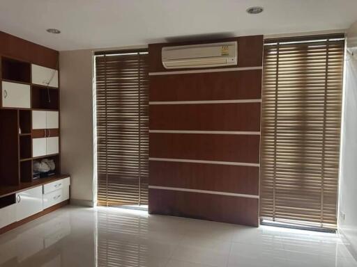 Living room with wooden blinds, shelves, and air conditioning