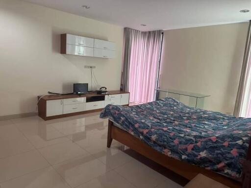 Spacious modern bedroom with natural light, tiled flooring, minimalist furniture, and a double bed