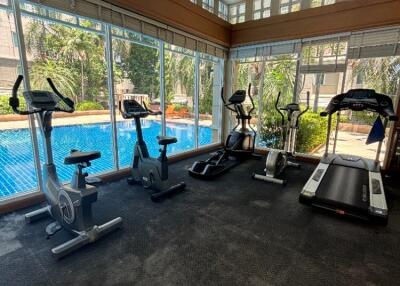 Fully-equipped fitness center with exercise machines and a view of the pool