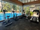 Fully-equipped fitness center with exercise machines and a view of the pool