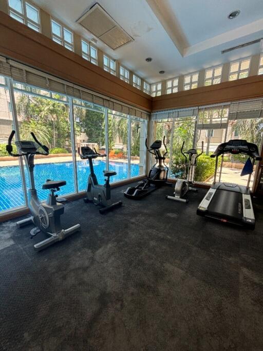 Fully-equipped fitness center with exercise machines and a view of the pool
