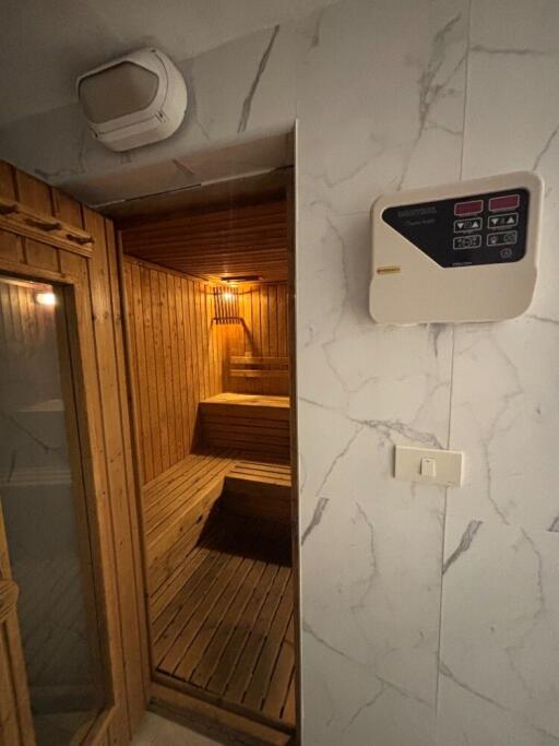 Indoor sauna with wooden interior and control panel on the wall