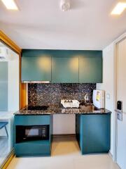 Compact modern kitchen with teal cabinets and black speckled countertop