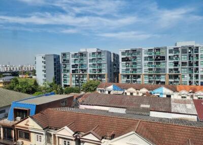 Cityscape view featuring modern apartment buildings and traditional houses under a blue sky