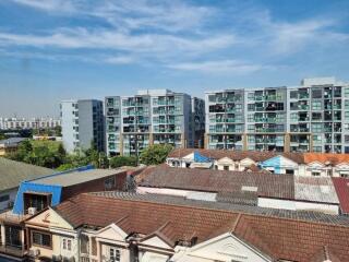 Cityscape view featuring modern apartment buildings and traditional houses under a blue sky