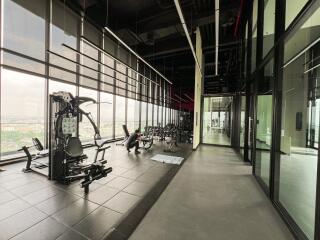 Modern fitness center with various exercise equipment and large windows