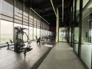 Modern fitness center with various exercise equipment and large windows