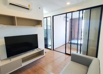 Modern living room with TV, air conditioner, and gray sofa