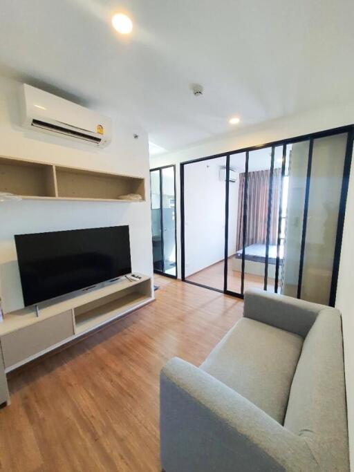 Modern living room with TV, air conditioner, and gray sofa