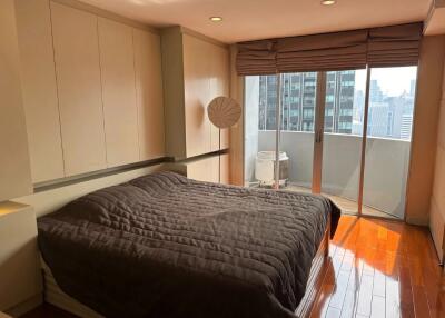 Modern bedroom with a large bed, balcony view, and wooden floors