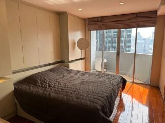 Modern bedroom with a large bed, balcony view, and wooden floors