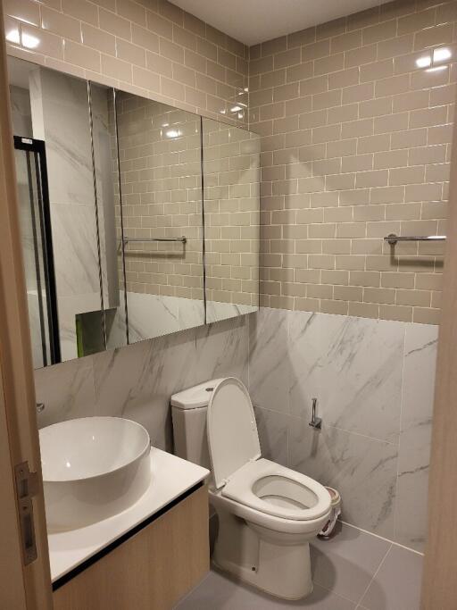 Modern clean bathroom with large mirror, toilet, and sink