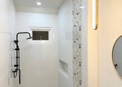 Modern bathroom with sleek white tiles, black faucet, and round mirror