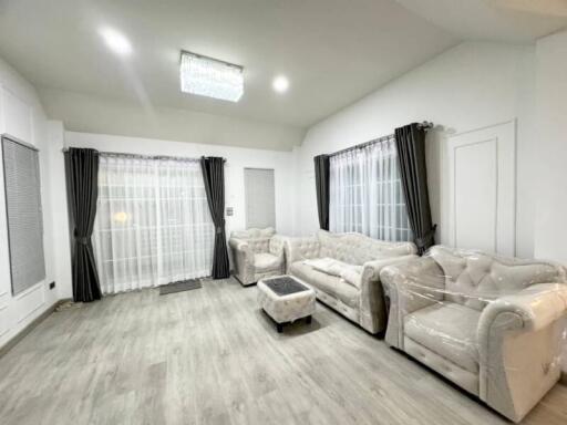 Spacious living room with grey curtains, light wooden flooring, and plush seating