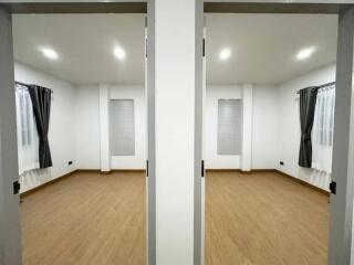 Dual bedroom spaces with wooden flooring and large windows