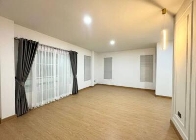 Spacious empty living room with wooden flooring and large windows