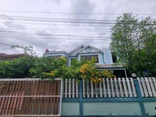 Exterior view of a residential house with a fenced garden