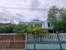 Exterior view of a residential house with a fenced garden